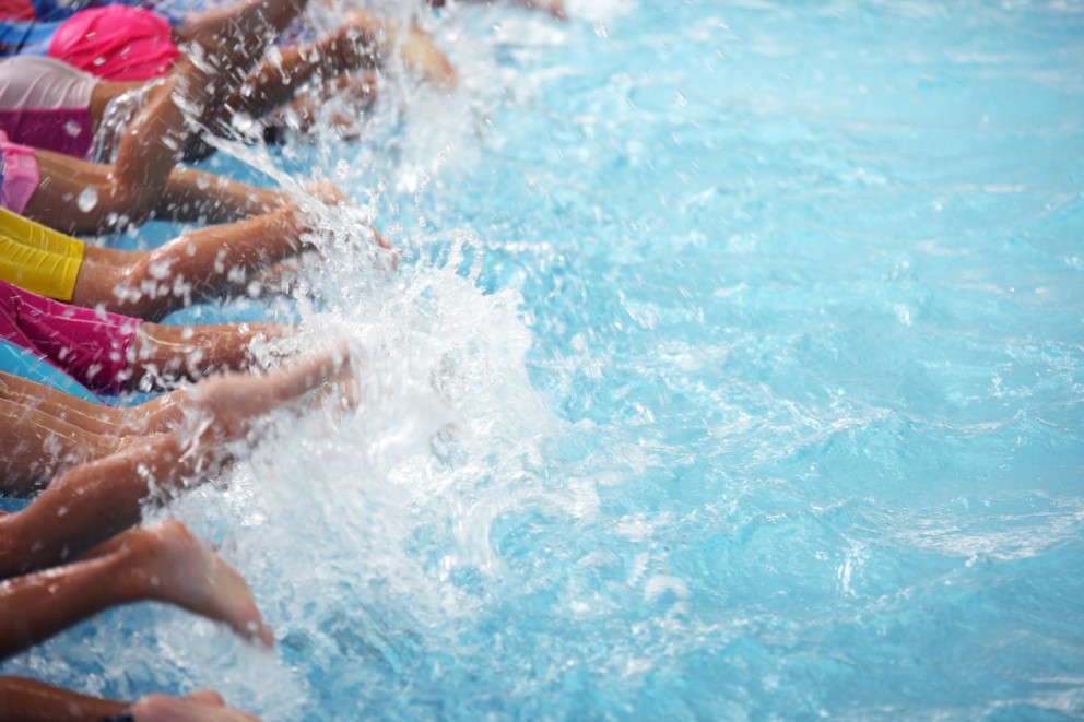 Beelden van kinderen die met hun voeten in het water spl splashen, met een helderblauwe water achtergrond.
